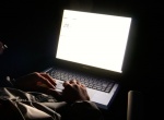 Man in dark night, face lit by blank white LCD laptop display light
